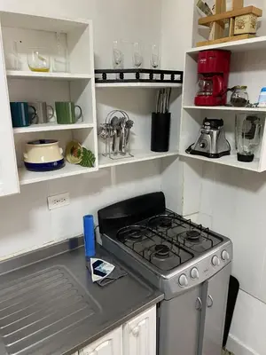 a kitchen with a stove and white shelves at Apartamento en Belén San Bernardo, Medellín in Medellín