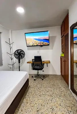 a bedroom with a bed and a desk and a tv at Apartamento en Belén San Bernardo, Medellín in Medellín