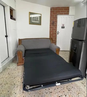 a bed in a room next to a refrigerator at Apartamento en Belén San Bernardo, Medellín in Medellín