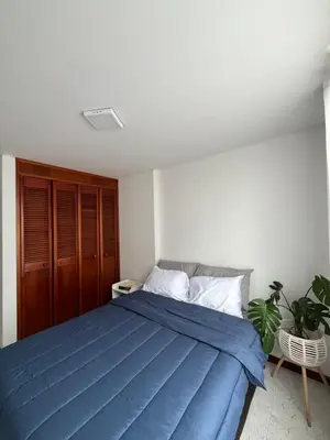 a bedroom with a bed with a blue blanket at Hermosa habitación con excelente ubicación in Medellín