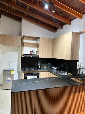 a kitchen with wooden cabinets and a black counter top at Refugio en laureles in Medellín