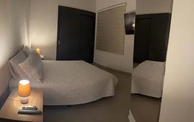 a bedroom with two beds and a table with a lamp at Refugio en laureles in Medellín