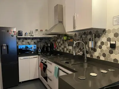 a kitchen with white cabinets and a black refrigerator at Casa Florez in Medellín