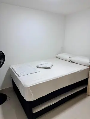 a bed with white sheets and towels on it at Apartamento balcón laureles estadio ED Milagros in Medellín
