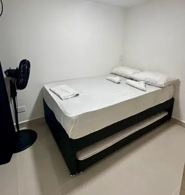 a bed in a room with white sheets and pillows at Apartamento laureles estadio 201 ED MILA in Medellín