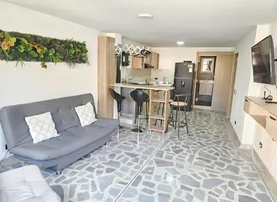 a living room with a couch and a kitchen at Exclusive Stadium Apartment in Medellín