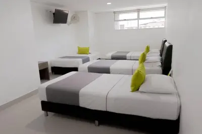 a room with four beds with green objects on them at 3H hotel centro histórico in Medellín