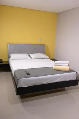 a large bed in a room with a yellow wall at 3H hotel centro histórico in Medellín