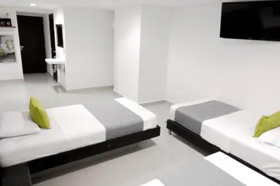 a bedroom with two beds and a flat screen tv at 3H hotel centro histórico in Medellín