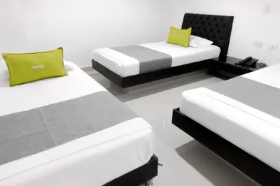 two beds in a room with white walls and yellow pillows at 3H hotel centro histórico in Medellín