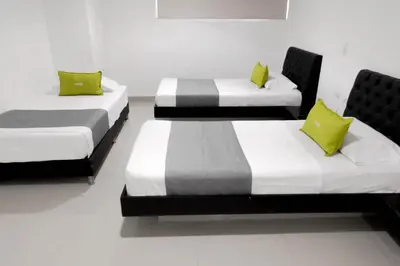 three beds with lime green pillows in a room at 3H hotel centro histórico in Medellín