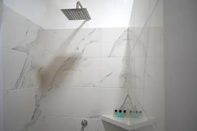 a bathroom with white marble walls and a shower at El Cortijo