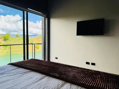 a bedroom with a bed with a flat screen tv on the wall at Exclusive Villa - Lake View - Forest in La Pradera