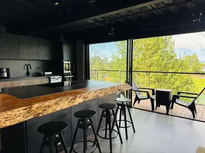 a kitchen with a counter with bar stools and a large window at Exclusive Villa - Lake View - Forest in La Pradera
