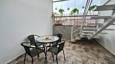 a table and chairs in a room with stairs at Dúplex familiar cerca al Cable y Milán con patio in Manizales