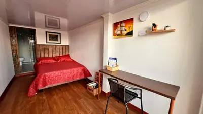 a small bedroom with a red bed and a desk at Dúplex familiar cerca al Cable y Milán con patio in Manizales