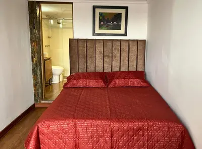 a red bed with a red comforter in a bedroom at Dúplex familiar cerca al Cable y Milán con patio in Manizales