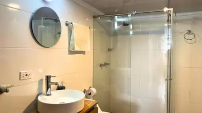 a bathroom with a sink and a shower with a mirror at Dúplex familiar cerca al Cable y Milán con patio in Manizales