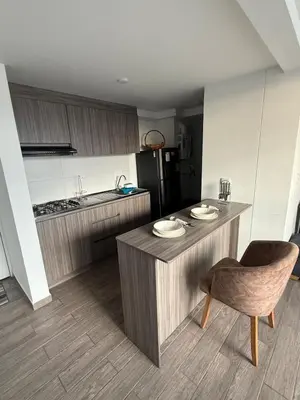 a kitchen with a table and a chair and a refrigerator at Simplemente en Casa! in Manizales