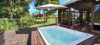 a hot tub on a deck with an umbrella at Casa de Campo Bheta in Guatapé