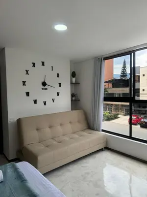 a living room with a couch and a clock on the wall at Faro 201, 202, 203 Lujo en Laureles Ubicación Premium in Medellín