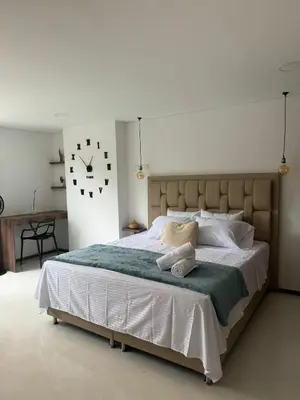 a bedroom with a large bed with a clock on the wall at Faro 201, 202, 203 Lujo en Laureles Ubicación Premium in Medellín