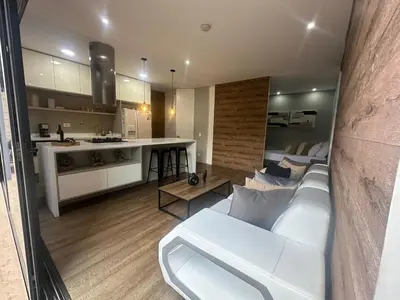 a living room with a white couch and a kitchen at Energy Living - Luxury Apartment with Jacuzzi and Private Terrace in Medellín