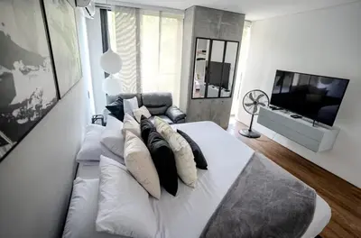 a bedroom with a white bed with pillows and a television at Energy Living - Luxury Apartment with Jacuzzi and Private Terrace in Medellín