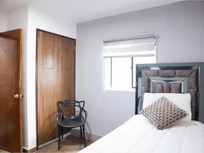a bedroom with a bed with a wooden headboard and a chair at Casa solare in Medellín