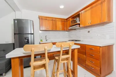 a kitchen with wooden cabinets and two chairs at a counter at Aptos Familiares en Envigado con Aire Acondicionado in Envigado