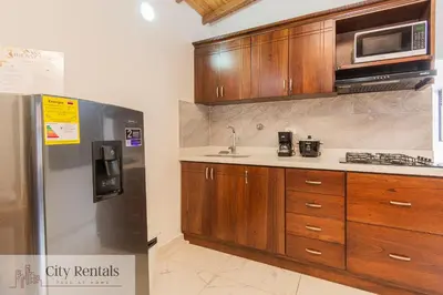 a kitchen with wooden cabinets and a stainless steel refrigerator at Aptos Familiares en Envigado con Aire Acondicionado in Envigado