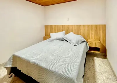 a bedroom with a large bed with a wooden headboard at Amplio apto 2 hab para familias y grupos Sabaneta in Sabaneta