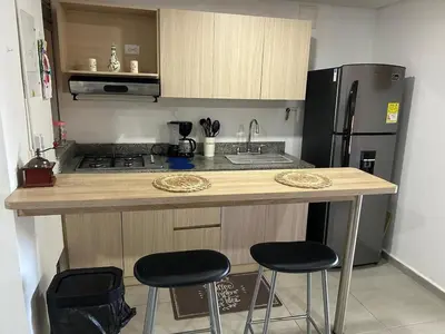 a kitchen with a counter with two stools and a refrigerator at Apartamento Living La Ceja in La Ceja