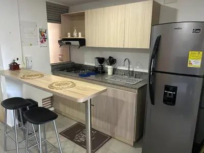 a kitchen with a refrigerator and a counter with stools at Apartamento Living La Ceja in La Ceja