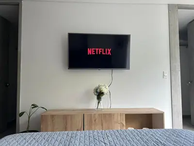 a television on a white wall with a vase of flowers at Apartamento Living La Ceja in La Ceja