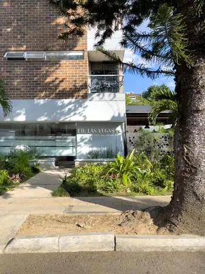 a building with a sign in front of a tree at Vegas PH Suites in Medellín
