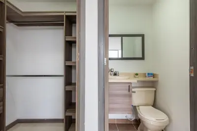 a bathroom with a toilet and a sink and a mirror at Vegas PH Suites in Medellín