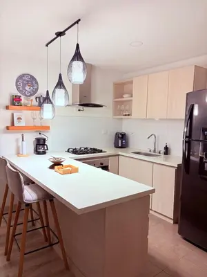 a kitchen with a white counter and a black refrigerator at Apartamento moderno con balcón y vista a la ciudad cerca al mall plaza in Manizales