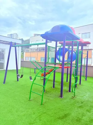 a playground with slides and swings on the grass at Apartamento moderno con balcón y vista a la ciudad cerca al mall plaza in Manizales