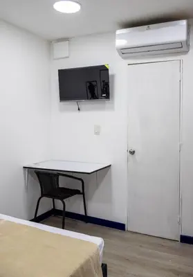 a room with a desk and a tv on the wall at S23 I City Lodge in Sabaneta