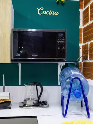 a microwave above a kitchen counter with a blue container at S23 I City Lodge in Sabaneta
