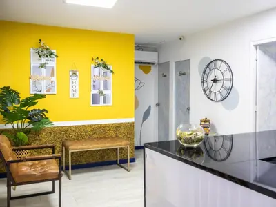 a lobby with yellow walls and a chair and a clock at S23 I City Lodge in Sabaneta