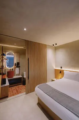 a bedroom with a large bed and a bathroom at Kuuna Medellín By Be Host in Medellín