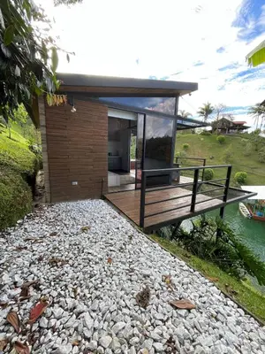 a small house on a river with a bench at Boreal Glamping in Guatapé
