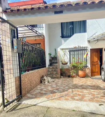 a cat laying on the ground in front of a house at Casa Bosques in Pilarica - Family and cozy in Medellín