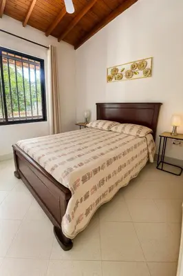 a large bed in a bedroom with a large window at Casa Bosques in Pilarica - Family and cozy in Medellín