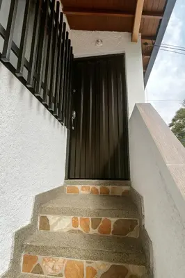 a black door on the side of a building with stairs at Casa Bosques in Pilarica - Family and cozy in Medellín