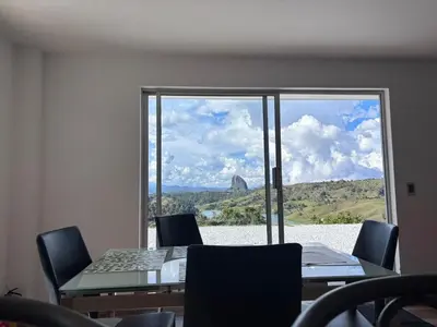 a room with a table and chairs and a large window at Finca El Encanto Guatapé in Guatapé