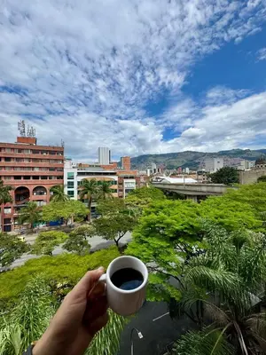 a person holding a cup of coffee in a city at Hotel Plaza Mayor 44 in Medellín