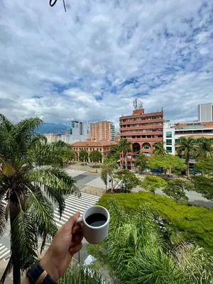 a person holding a cup of coffee in a city at Hotel Plaza Mayor 44 in Medellín